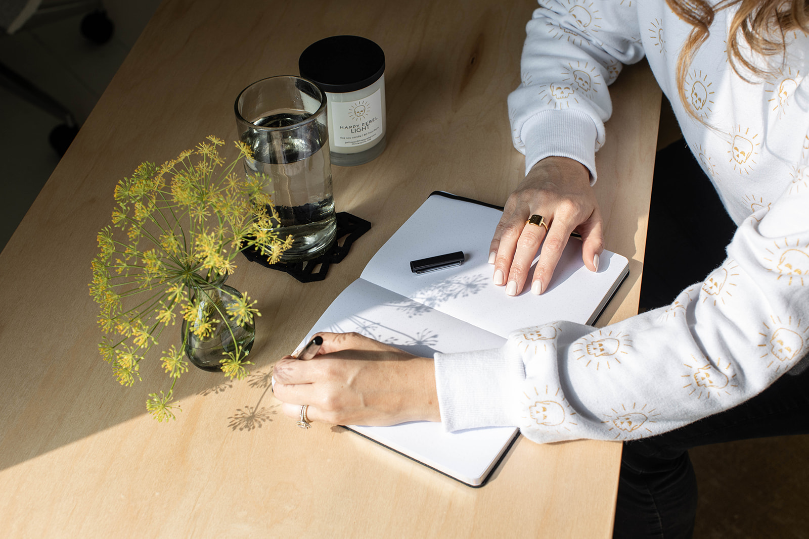Woman at a desk with gratitude journal and pen.